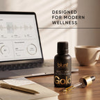 Blunt Essential Gold CBD THC oil bottle on a desk with a laptop and cup in the background, text 'Designed for Modern Wellness'.